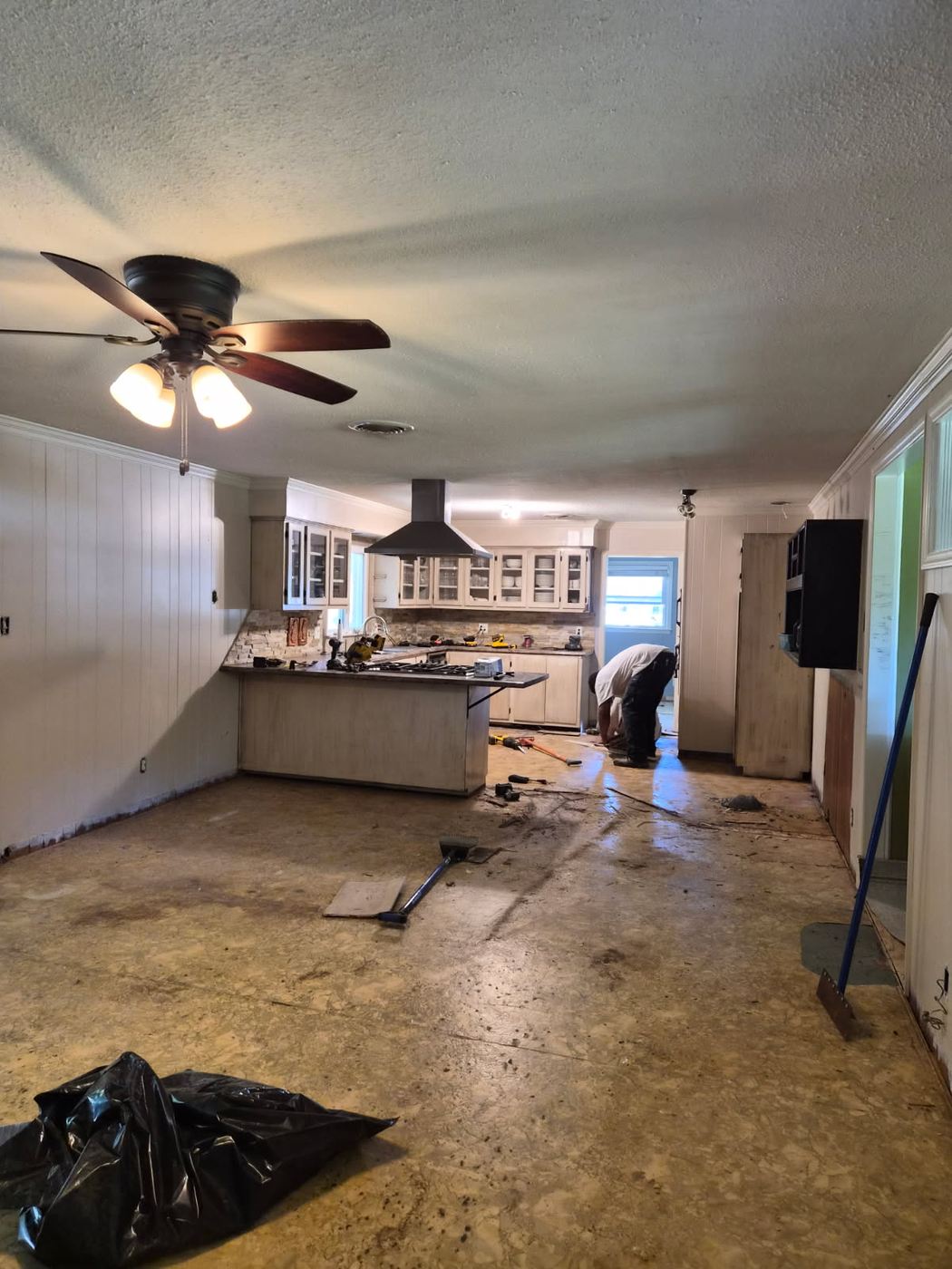 Kitchen and living room in an Alamance County NC home stripped back with the popcorn ceiling still up and flooring removed down to the slab