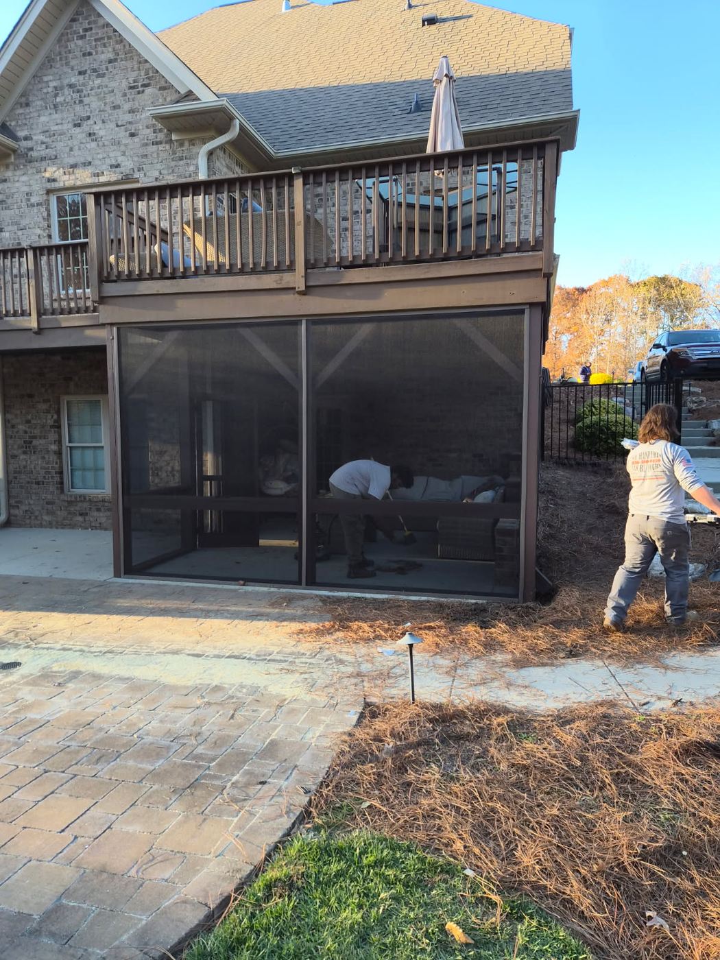 Screened porch built in underneath a raised wooden deck at the back of a brick home near Burlington NC
