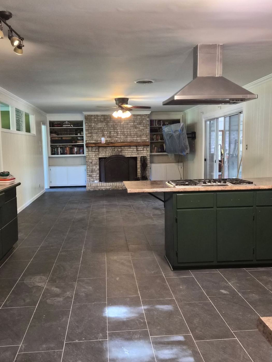 Finished open kitchen and living room with new tile flooring, smooth ceiling after texture removal, brick fireplace and built in bookcases
